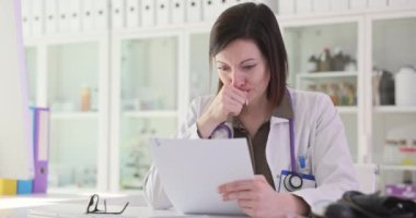 Üzgün doktor, klinik 4K filminde ağır çekimde kanser olan hastanın test sonuçlarını okuyor. Kanser hastaları konseptiyle çalışan tıbbi personelin sorunları