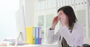Şaşırmış kadın doktor bilgisayar ekranının önünde gözlüklerini çıkarıyor ağır çekimde 4K film. Tıp konseptinde endişe sorunu