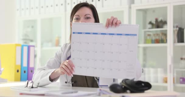 医師の婦人科医は クリニック4K映画のスローモーションでカレンダーを表示します 女性の概念における定期的な月経周期 — ストック動画