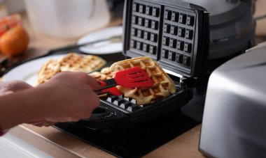 Mutfakta waffle ızgarasında Belçika waffle 'ı. Bitmiş Belçika wafflelarını fırın konseptinden çıkardı.