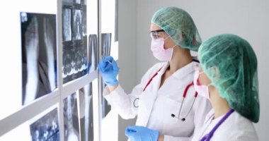 Koruyucu maske takan ve gözlük takan iki doktor röntgen yayınlıyor..
