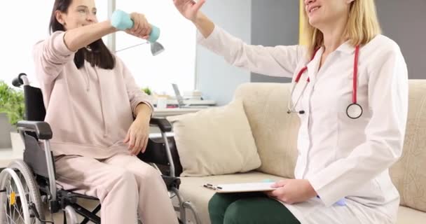 康复医生帮助坐轮椅的妇女做哑铃运动 帮助病人恢复丧失的健康功能和恢复正常生活的概念 — 图库视频影像
