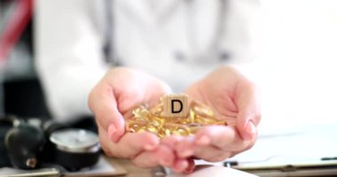 D vitamini kapsüllü kadın beslenme uzmanı elleri. Doktor diyet kliniğinde ilaç ve vitamin reçetesi yazıyor.
