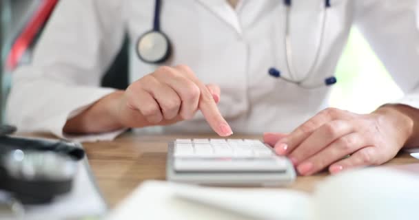 医師の手は医療費の計算機を使った 医療保険費用記号 — ストック動画