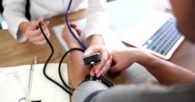 Kadın doktor kalp atış hızı monitörüyle yüksek tansiyon ve kalp atış hızını ölçer. Kardiyolog, hastaya tonometre ile kan basıncını ölçer.