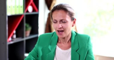 İş yerinde uykulu ve yorgun bir şekilde oturan genç bir kadının portresi. Çekici iş kadını evde esniyor, dinleniyor ya da sıkılıyor.