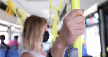 Korumalı maskeli kadın trenin içinde güvenlik için tırabzanları tutuyor. Taşıma güvenliği ve maske modu kavramı