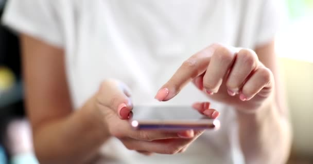 女性は携帯電話で本を読むか ニュースフィードをスクロールするソーシャルネットワークを使用しています スマートフォンの画面は 手の指を閉じてページを反転 — ストック動画