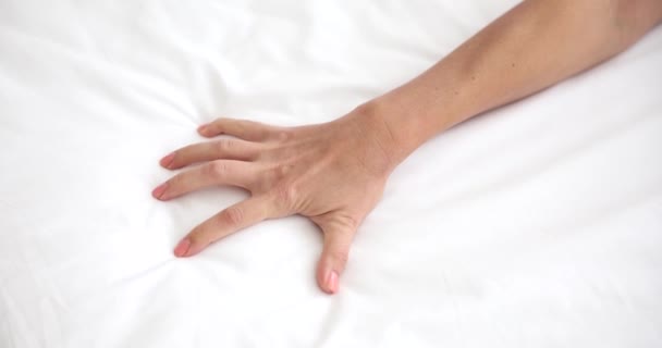 女の手は情熱的にベッドの上にシートをクラッチ ベッドの上で若い女性の近さ — ストック動画