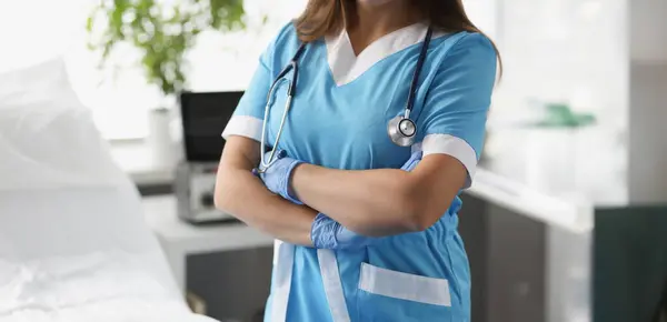 Woman doctor with crossed arms standing in hospital ward closeup. Severe patient care concept