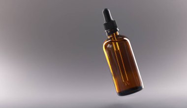 Gri arka planda kozmetik yağlı cam şişe. Kozmetik ürünleri konseptinin kozmetik satışı