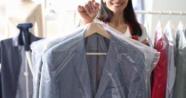 Smiling receptionist at dry cleaning hands over clothes to client. Quality dry cleaning services concept