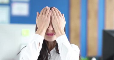 Young woman covers eyes with hands and shakes head. Fear and denial concept