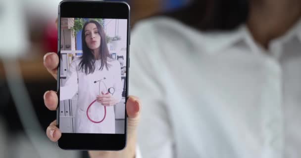 医師とビデオ通話をするために携帯電話を使用して女性 医者は遠隔医療の助言を与え 治療を説明する 遠隔医療遠隔コンサルティング — ストック動画