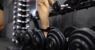 Spor eğitimi için spor salonundaki halterli erkek sporcu ağır çekimde 4K film izliyor. Sağlıklı yaşam tarzı kavramı