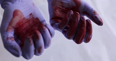 Kauçuk koruyucu eldivenli cerrahın elini sıkarak 4K 'lık yakın çekim filmi ağır çekimde. Ölümcül sonuç kavramına sahip başarısız cerrahi operasyonlar