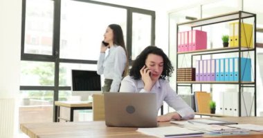 İş arkadaşları ofis 4K filminde müşterilerle cep telefonundan konuşuyor. İş görüşmesi ve planlama çağrısı