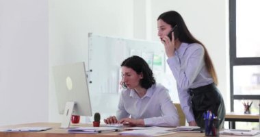 İş ortağı erkek ve kadın bilgisayar başında çalışıyor ve ofis 4K filminde cep telefonuyla konuşuyorlar. İş geliştirme stratejileri kavramı