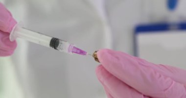 Klinikteki ampulden şırıngaya ilaç çeken hemşire 4K 'lık filmi yavaş çekimde çekiyor. Uyuşturucu kavramının damar içi ve kas içi yönetimi