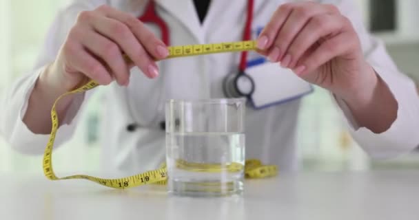 医生营养学家用厘米长的胶带和4K胶卷测量一杯水 适当的营养和适当的液体摄入概念 — 图库视频影像