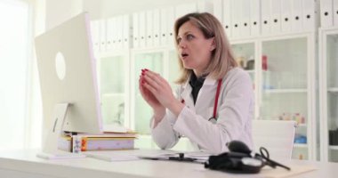 Üzgün kadın doktor bilgisayar ekranına bakıyor ve klinik 4k filminde ağır çekimde hasta analizinin kötü sonuçlarını görüyor. Teletıp konsepti sorunları
