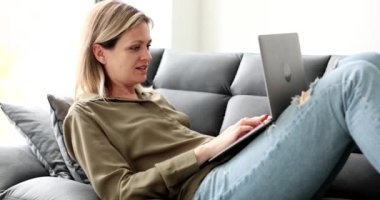 Genç bir kadın dizüstü bilgisayarla kanepeye oturmuş internette sohbet ediyor. Serbest çalışmak ve ev kavramından uzak durmak