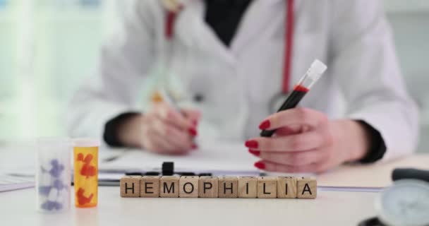 Dokter Houdt Reageerbuis Met Bloed Buurt Van Woord Hemofilie Houten — Stockvideo