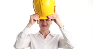 Kadın mühendis sarı koruyucu inşaat başlığı takıyor. Beyaz arka planda 4K film yavaş çekim. İnşaat alanı kavramında güvenlik