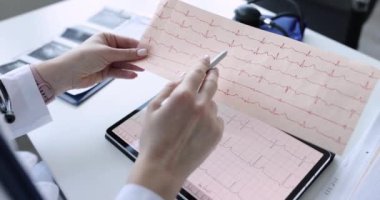 Doktor kardiyolog tabletteki elektrokardiyogramı inceliyor. Kalp ağrısı ve tıbbi muayene konsepti