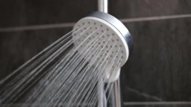 Banyodaki duş musluğundan akan su telleri 4K 'lık yakın çekim filmi. Sabah hijyen prosedürleri duş konseptini alıyor