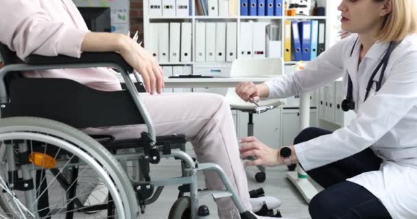 神经学家医生用锤子敲坐在轮椅上的妇女的腿 下肢无力和感觉丧失的概念 — 图库视频影像