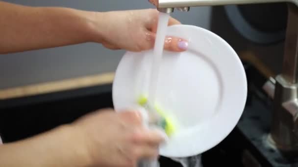 主婦の手は 水をタップの下にスポンジや洗剤で白いプレートを洗うクローズアップ4K映画 家事労働の概念 — ストック動画