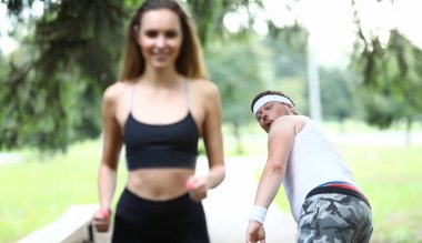 Şişko Adam, spor kızına hevesle bakıyor. İnsanlar parkta düşük hızda hareket eder. Başarı ruh haline ve motivasyon atletine bağlıdır. # Adam dalgalanmanın gücünü görür # # Eğitilmiş güzel kız #.