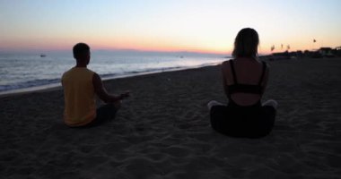 Çiftler gün batımında birlikte yoga ve meditasyon yapıyorlar. Aşk, ilişkiler ve rahatlama kavramı