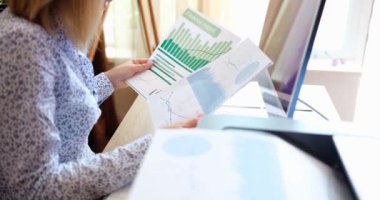 İş kadını, mali tablolara ve ofisteki grafiklere bakıyor. Muhasebe istatistikleri ve analitik araştırma kavramı