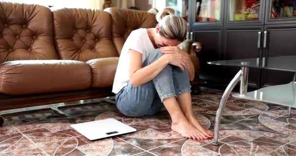 身体のマサを測定するためにスケールの横に床に座って泣いている女性 太りすぎのうつ病やストレス — ストック動画