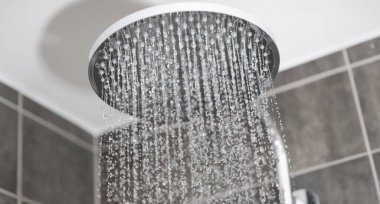Banyodaki metal yağmurdan gelen su küçük jetlerde akıyor. Sabah hijyen prosedürleri kavramı.