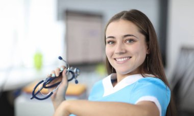 Close-up of cheerful therapist looking at camera with happiness and smile. Beautiful practitioner holding stethoscope. Healthcare and medicine concept clipart