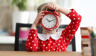 Bebek elbisesi yüzünü büyük bir çalar saatle kapladı. Nöbetteki numaraları ve numaraları öğren. Mekanik saat ile elektronik saat arasındaki fark. Pratik görevler oyun saati