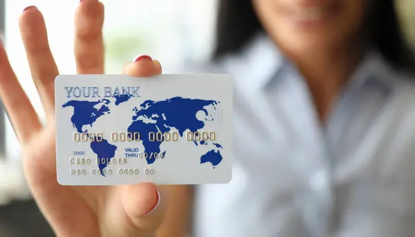 Woman arm holding banking card showing it to camera close-up