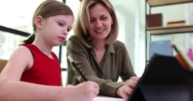 Küçük kız öğretmeniyle çalışıyor. Evde tablet kullanıyor. Film ağır çekimde. Okul konsepti için özel ders hazırlama