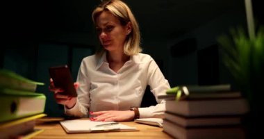 İş kadını gecenin geç saatlerinde fırtına 4K filmi sırasında ofise koşuyor ve saat ve cep telefonuna bakıyor. Son teslim tarihi yıllık rapor kavramı