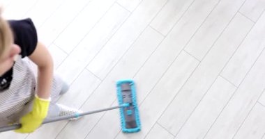Önlüklü ev hanımı ve ofis manzarasında yerleri silen lastik eldivenli. Ev ve ofis konsepti için temizlik hizmetleri
