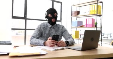 Kar maskeli dolandırıcı ve kulaklıklı 4K video bağlantısı ile cep telefonundan konuşuyor. İnternet dolandırıcılığı kavramı