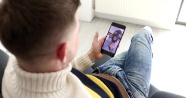 Adam cep telefonuyla video bağlantısı üzerinden internet dolandırıcısı ile iletişim kuruyor ve banka kartı 4K filmi gösteriyor. Çevrimiçi dolandırıcılık kavramı