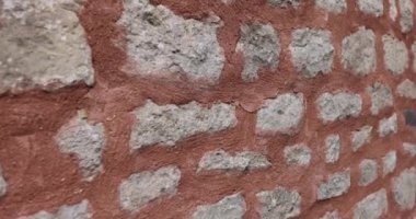 Şehir sokağındaki kırmızı çimento ve taştan duvar. 4K 'lık yakın çekim. Ağır çekim. Binaların tasarımı ve mimarisi