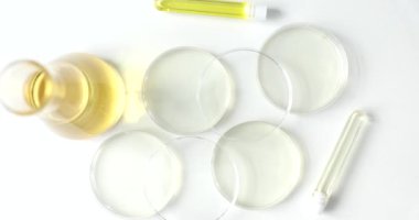 Cam laboratuvar çanakları ve sarı sıvılı mataralar, yukarıdan, yakın plan. Kimyasal inceleme ekipmanı