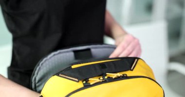 Genç kadın elleri, sarı bir sırt çantasına dizüstü bilgisayar koymuş. Yakın plan. Suç ortağı, hafif seyahat eden, yavaş çekim