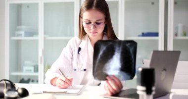 Genç doktor elinde bir röntgen tutuyor ve yakın çekim yazıyor. Hastalığın teşhisi ve yaralanma, florografi