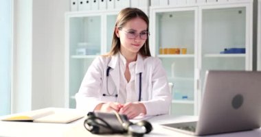 Genç doktor dizüstü bilgisayarın videosunda konuşuyor, yakın plan. Bir tıp uzmanının uzaktan konsültasyonu